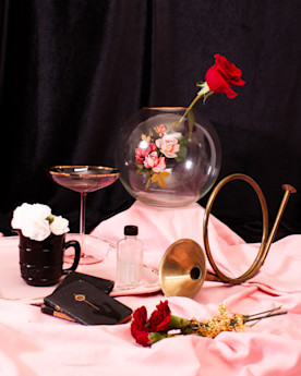 a photo of assorted objects arranged in a stylized composition, including roses, a brass horn, and small leather bound books