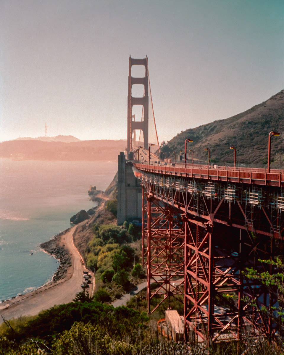 a photo of the Golden Gate Bridge with the shoreline visible on the left hand side
