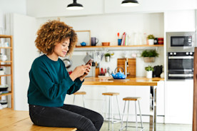 Woman sitting in kitchen on phone