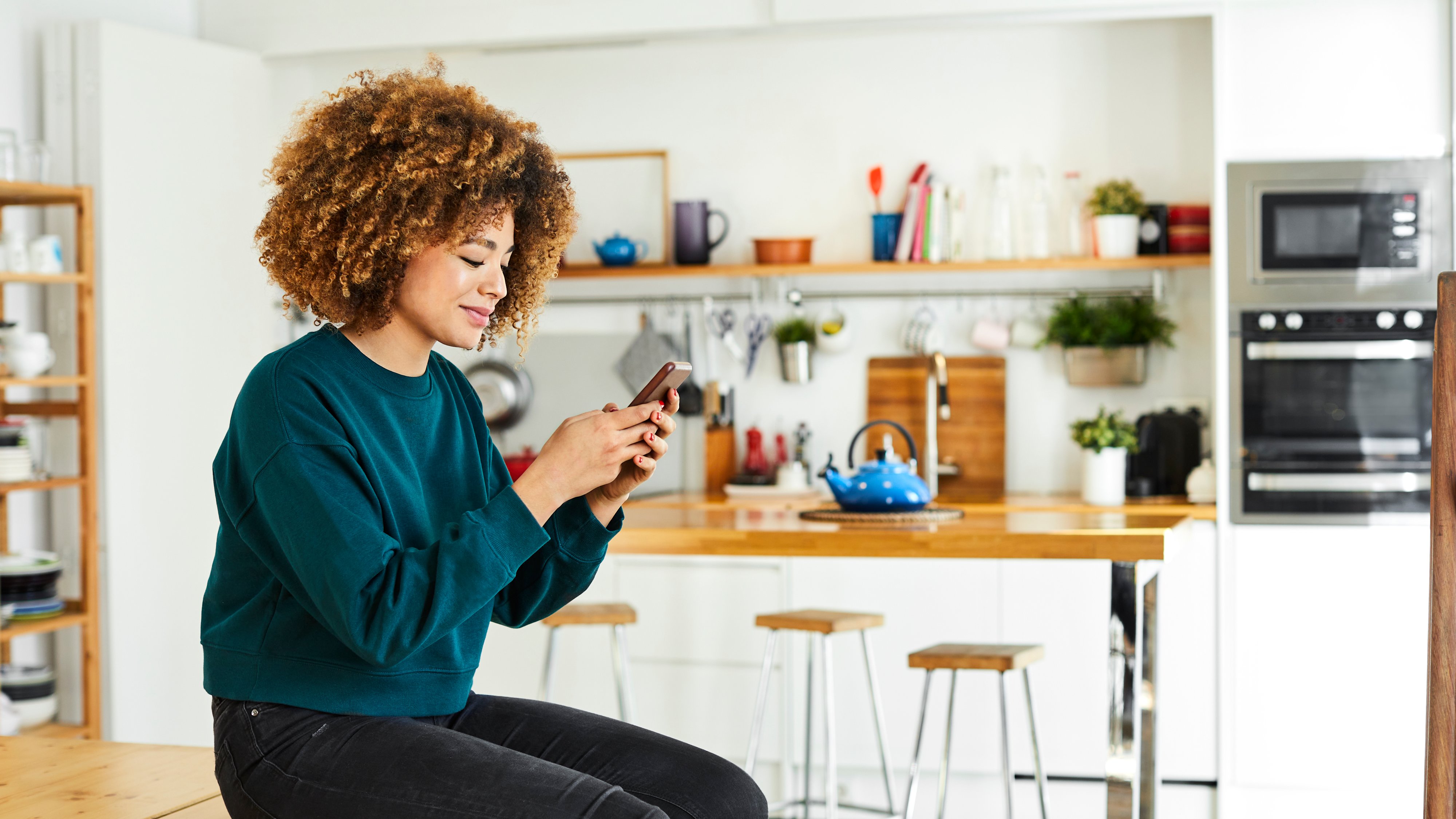 Woman sitting in kitchen on phone