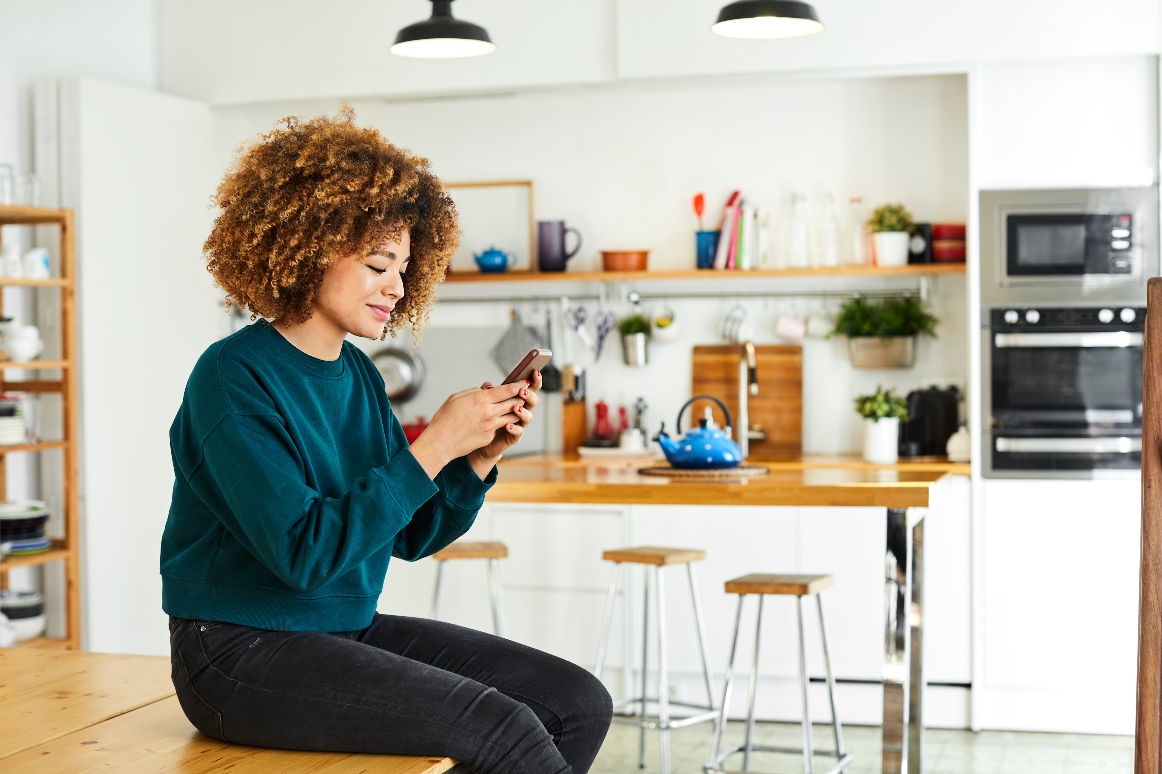 Woman sitting in kitchen on phone