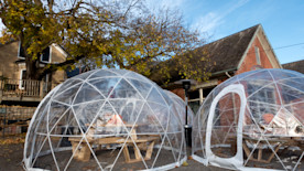 A restaurant provides large, see-through geodesic domes for outdoor dining.