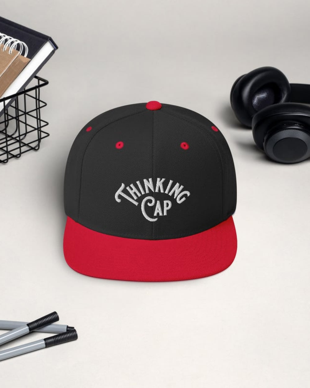 A black and red flat-brimmed hat that reads “Thinking Cap”