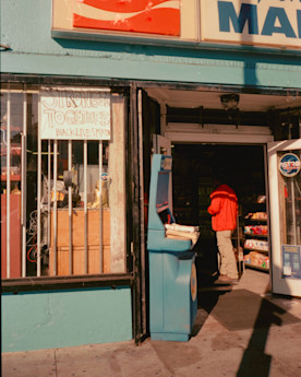 a photo of a market taken from the outside with a person standing near the doorway