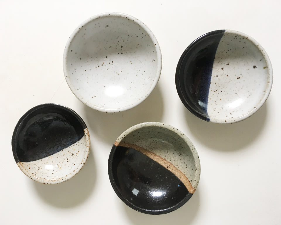 an overhead shot of four bowls with black and earth tone accents