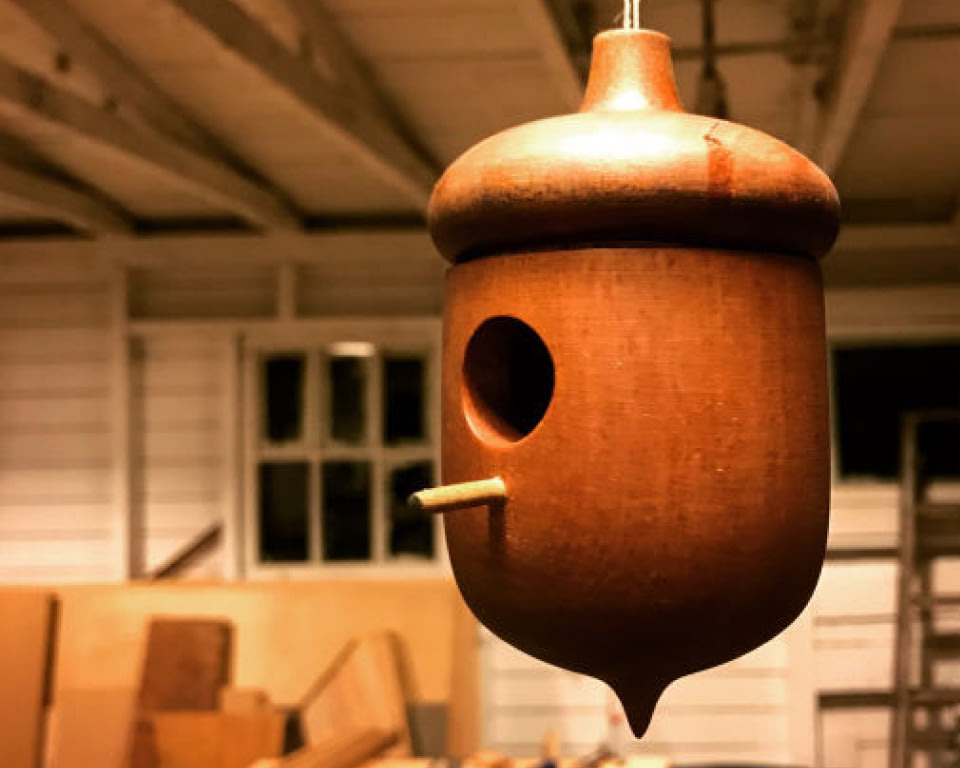 a hanging wooden bird house in the likeness of an acorn