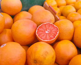 a photo of a pile of blood oranges with one orange cut in half