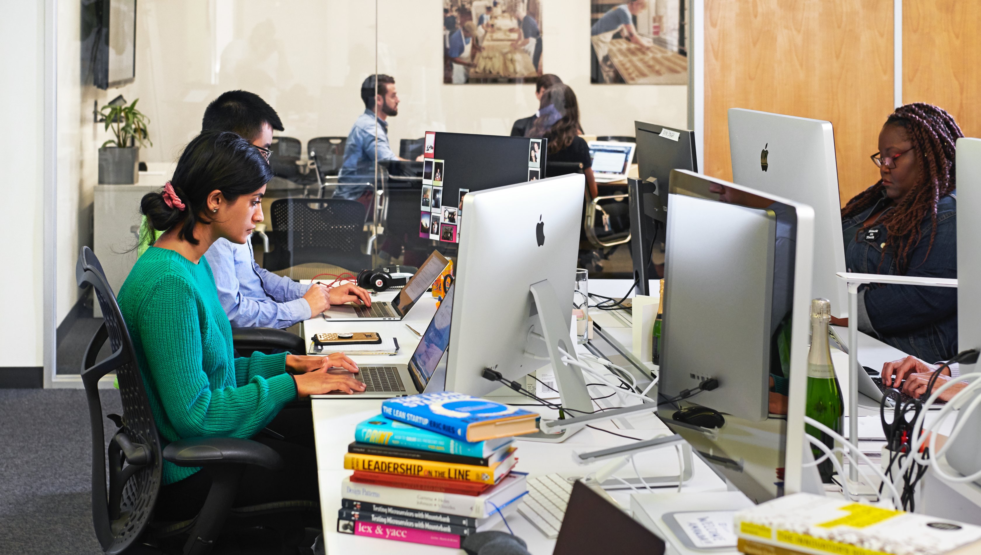 photo of people working at a shared desk space with large monitors
