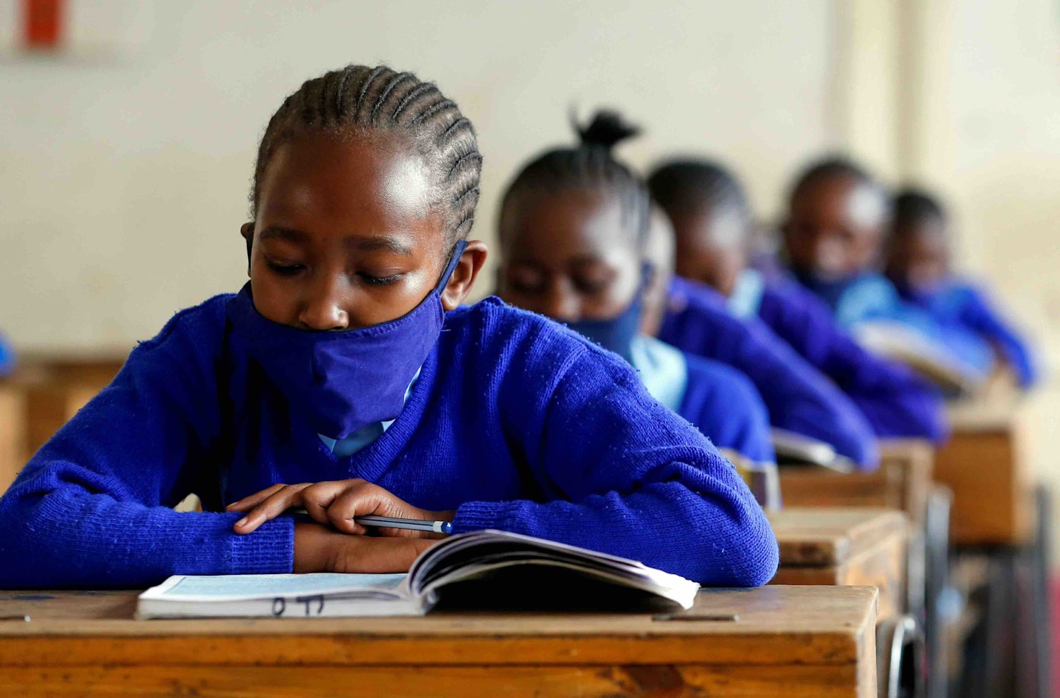 A schoolgirl wears a face mask as she reads a book inside a classroom at the Olympic Primary School during the partial reopening of schools in Nairobi