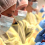 Three international students in the KU pharmacy program wearing PPE stand side by side in a lab