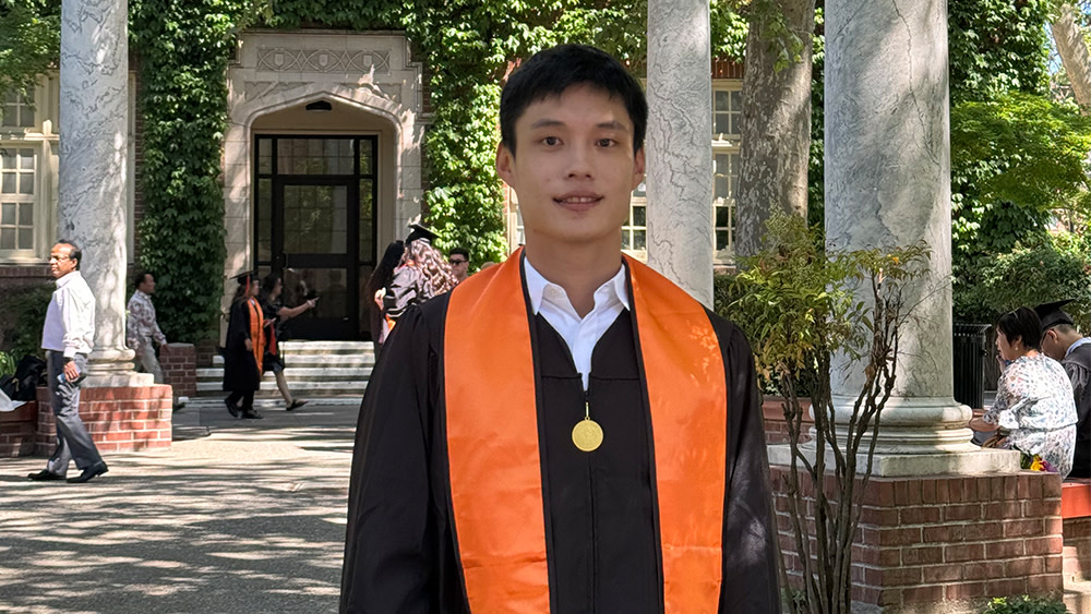 Ming-Hao, aka Howard, an international student at the University of the Pacific, stands on campus in his graduation gown after earning his graduate degree in computer science.