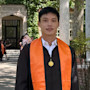 Ming-Hao, aka Howard, an international student at the University of the Pacific, stands on campus in his graduation gown after earning his graduate degree in computer science.