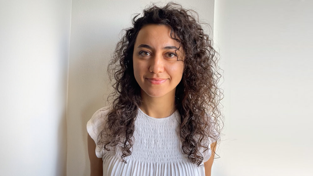 Asiye from Turkey, student advisor at the University of South Carolina International Accelerator Program, stands outside on the USC campus and smiles for the camera.