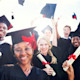 A group of smiling graduates in caps and gowns holding their diplomas
