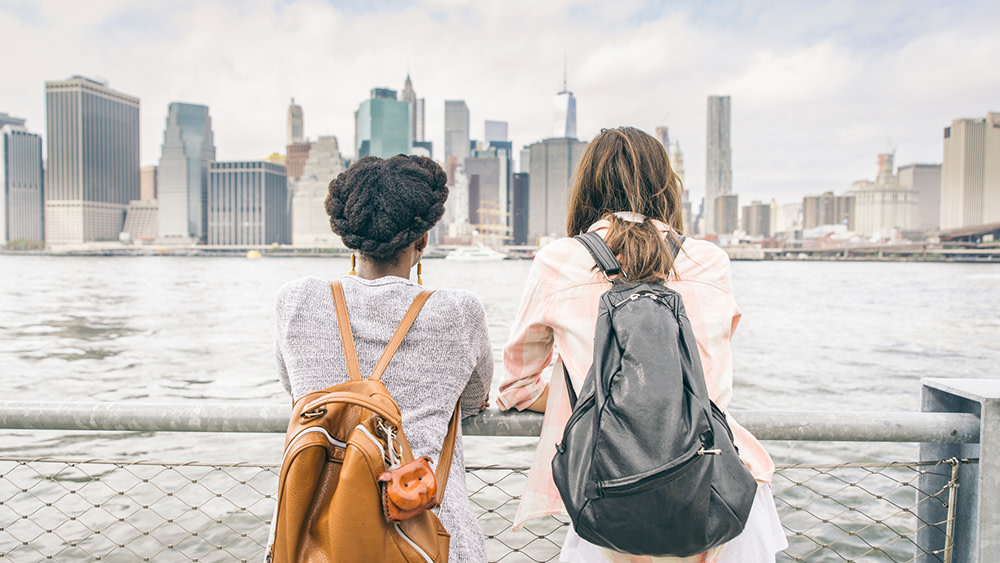 Two international students looking at a waterside view of NYC