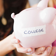 Two female international students hold out a piggy bank with the word COLLEGE taped on it