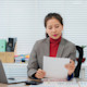 An Asian female student studying for a degree in business administration at her US university sits at a desk and studies a report.