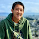 Li, an international student from China, sits overlooking the San Francisco Bay and smiles for the camera.