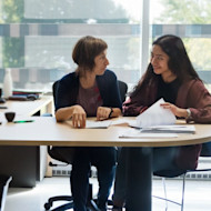 Two women, an international student and a counselor, discuss possible US university majors, while sitting at a desk.