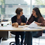 Two women, an international student and a counselor, discuss possible US university majors, while sitting at a desk.