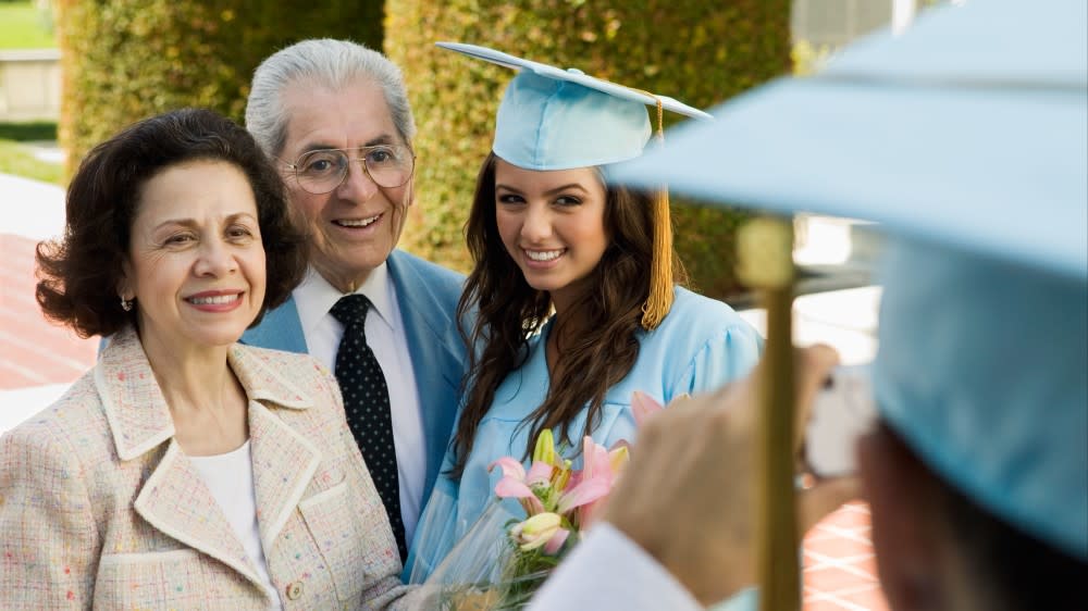 Mother and father with daughter in her graduation attire.