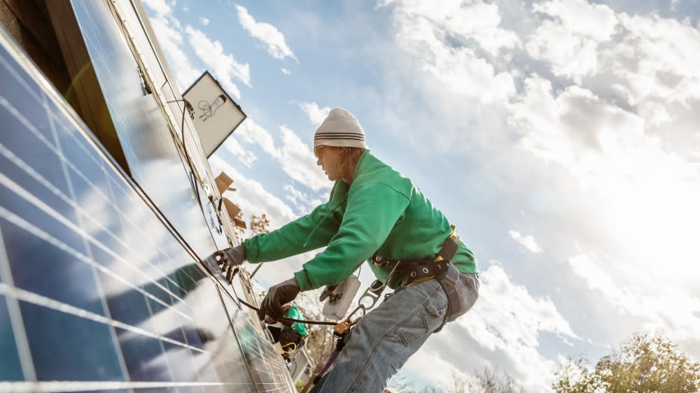 An international student at University of the Pacific installs solar panels against a bright sky