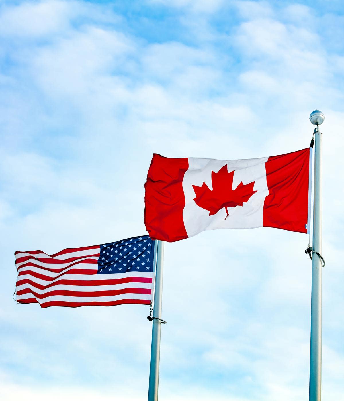 US universities or Canada universities - which should an international student choose? This photo shows US and Canadian flags flying on adjacent flagpoles.