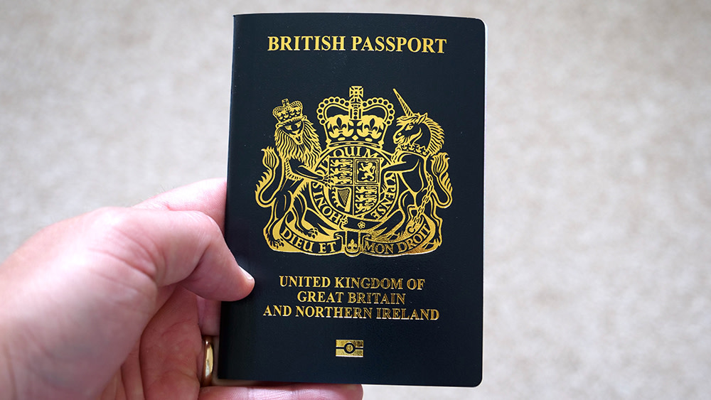 A hand holds a British passport for the United Kingdom of Great Britain and Northern Ireland