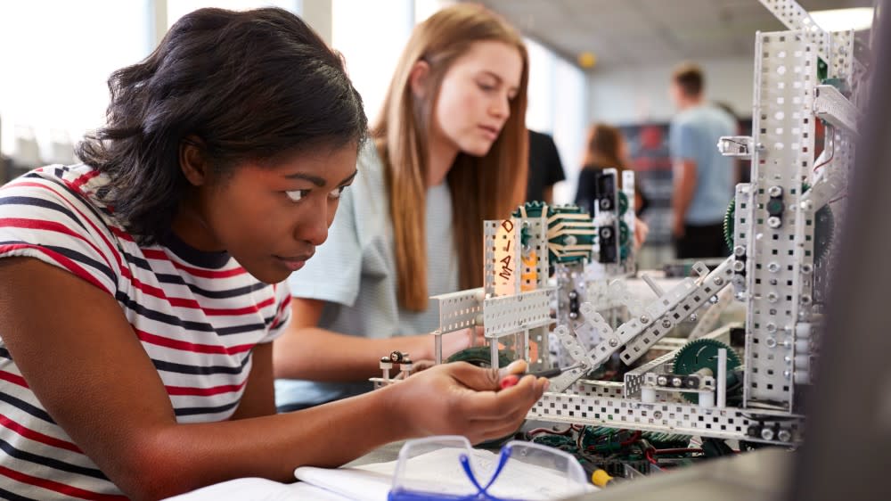 In this photo, two female international students in vocational study construct an engineering project at a table, a protective visor is laid on top of an open book. What are vocational courses? A vocational course means trade-focused studies at vocational colleges, including engineering, carpentry, and computer science.