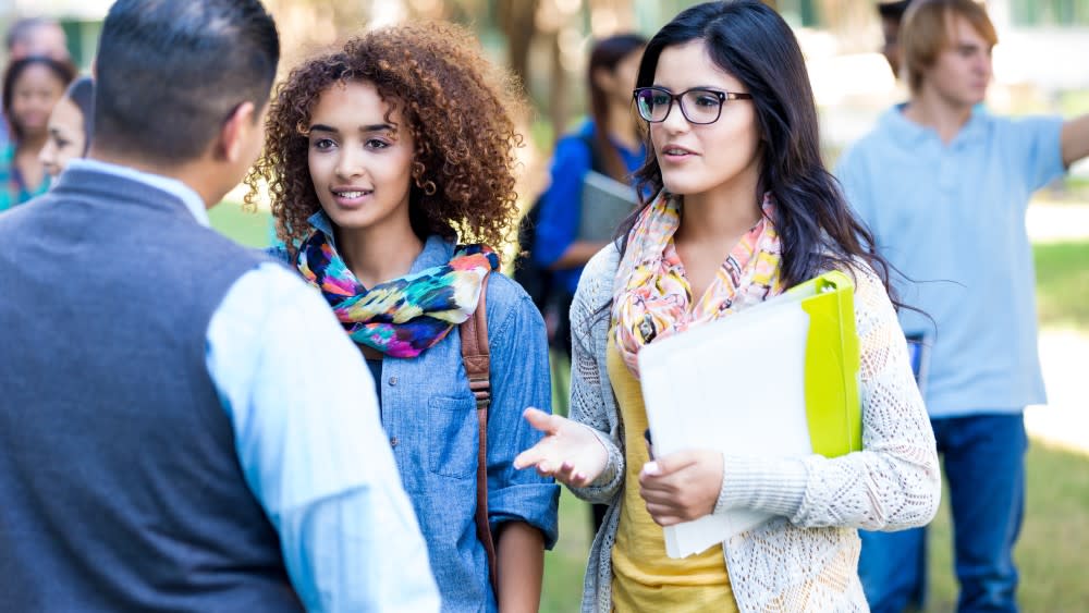 Three international students, two female students, and one male having a conversation about upcoming orientation programs at their US university orientation.