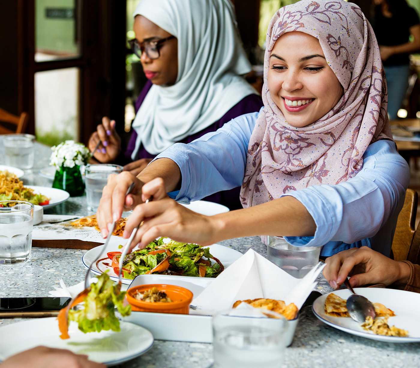A group of female international students wearing hijab share a halal meal at their US university during their you are welcome here orientation dinner.