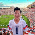 Justin from Taiwan, an international student studying supply chain management at Auburn, stands in the football stadium wearing a football jersey with the number one on the front