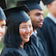 A female international student from Asia wearing a cap and gown stands among fellow graduates on her graduation day at a US university
