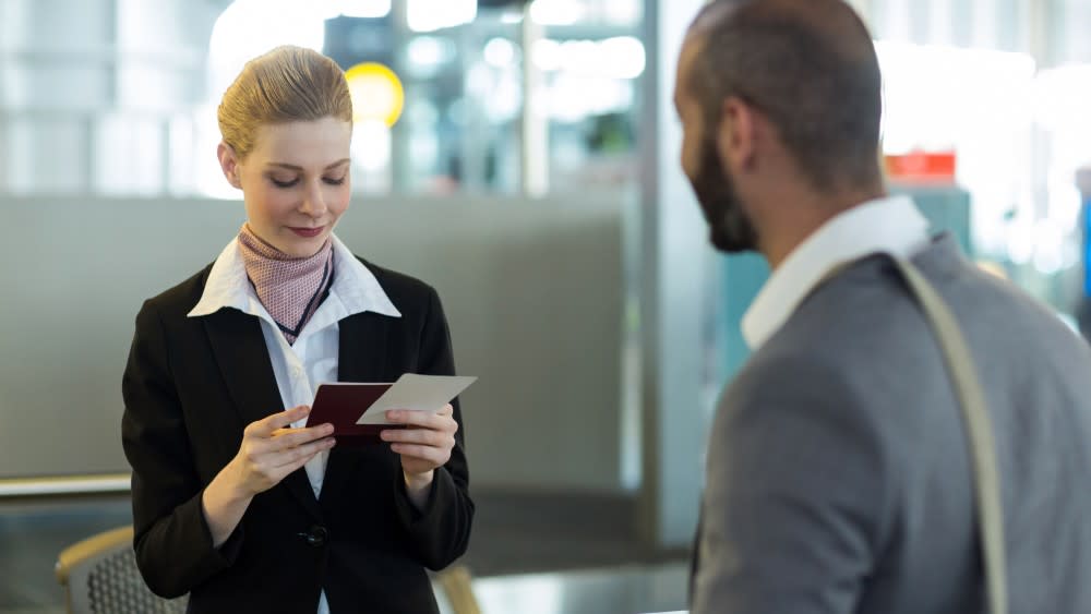 An international student at an airport, getting their passport and visa checked by airport staff, following successfully answering their f1 visa interview questions after rejection.