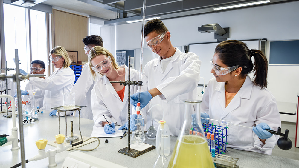 A group of international students wearing lab gear work on an experiment at their top-ranked US university.