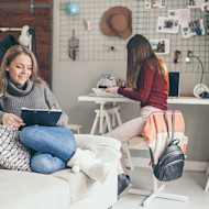 Two female international students studying in their shared decorated dorm room