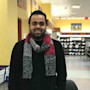 Yash, an international student at Louisiana State University, stands at his campus office during his campus job and smiles for the camera