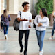 A male and female student with backpacks and carrying notebooks and walking while having an animated discussion.