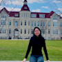 Ivy, an MBA candidate and international student from Vietnam, sits on a stone wall on the Carroll University campus.
