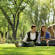 A group of four international students sits on a lawn under a grove of trees on the quad at their US university campus during the spring semester