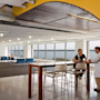 A female international student sits at a table at the University of Massachusetts Boston Venture Development Center startup incubator and speaks to a professor in a lab coat