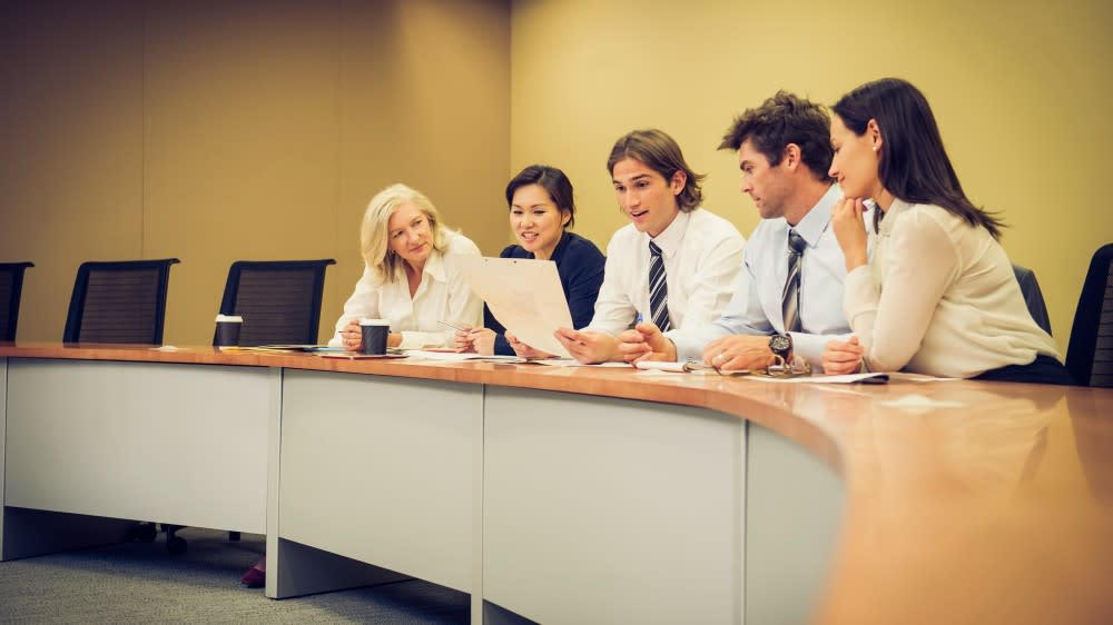 A group of international students in the MBA program at Gonzaga University sit in a row wearing professional attire for a mock business presentation