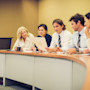 A group of international students in the MBA program at Gonzaga University sit in a row wearing professional attire for a mock business presentation
