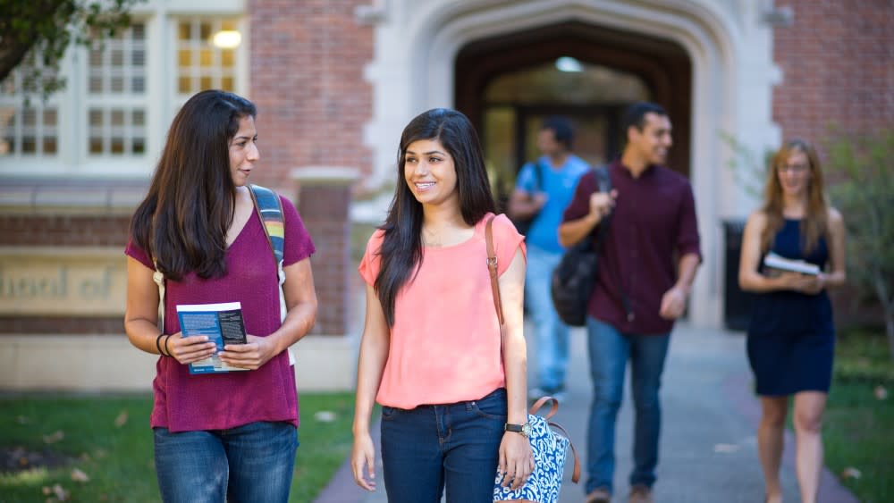 Two female international students walk outside after class and talk on the University of the Pacific campus