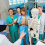 International nursing and medical students studying at medical colleges in the US stand in scrubs while being taught on site at a local hospital near their university.