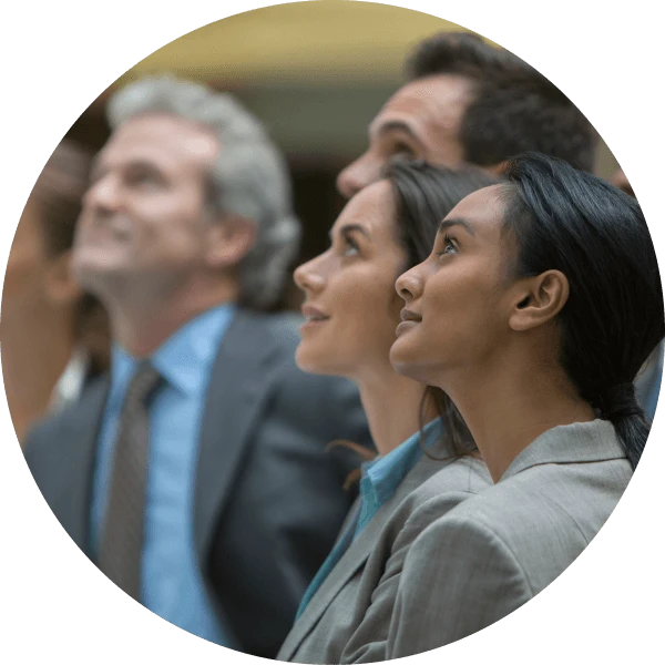 A group of four individuals look upwards. They are all dressed in professional attire, with suits and ties.