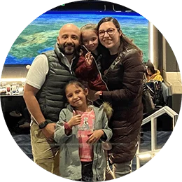 An adult woman, adult man, and two young girls pose together in the Space 220 Restaurant at the Walt Disney World Resort. The restaurant windows simulate a panoramic view of Earth from outer space.
