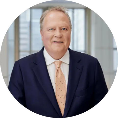 Jon R. Moeller, Charmin of the Board, President and Chief Executive Officer, is smiling at the camera. He is wearing a suit and a light orange tie.