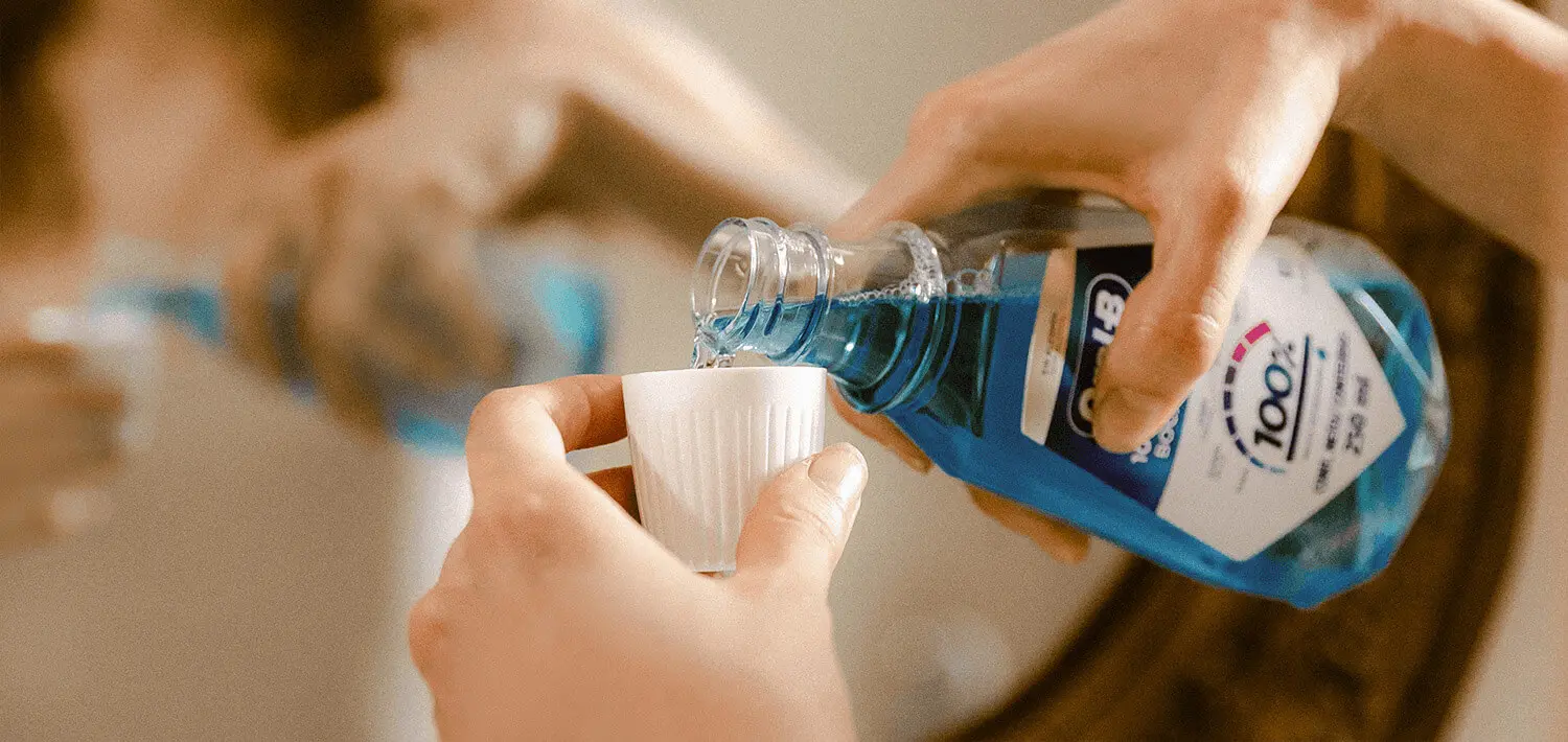 Osoba nalévající ústní vodu do uzávěru láhve