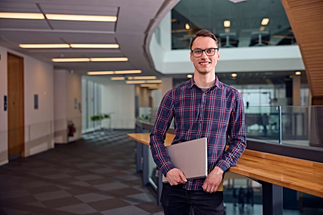 Man holding laptop smiling at the camera